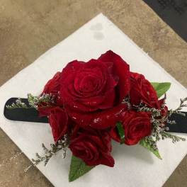 Red rose corsage with black ribbon on a white napkin