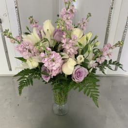 Pastel bouquet of roses, lilies, and pink stock in a glass vase