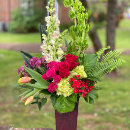 Tall mixed bouquet in a red vase with roses, snapdragons, and tulips