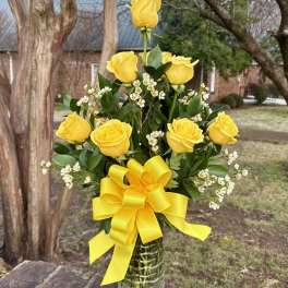 Yellow roses in a glass vase with a large yellow bow