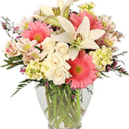 Bouquet of pink gerbera daisies, white lilies, and cream roses in a glass vase