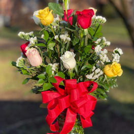 Mixed roses in a glass vase with a red ribbon bow