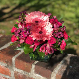 Pink gerbera daisies and roses in a glass vase