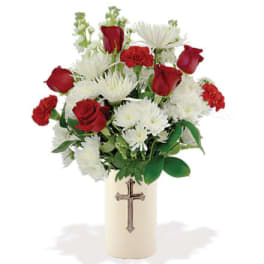 Red roses and white daisies in a cream vase with a cross emblem