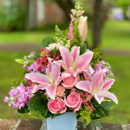 Pink lilies and roses in a square glass vase