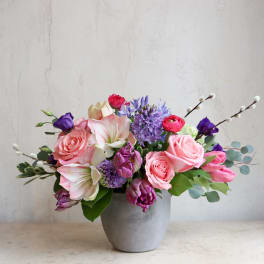 Pink and purple mixed flower arrangement in a gray vase
