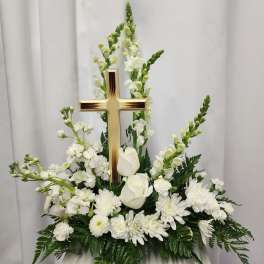 White floral funeral arrangement with a wooden cross centerpiece