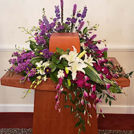 Purple and white floral arrangement on a wooden cross