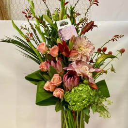 Tall mixed bouquet in a clear glass vase with pink and red blooms