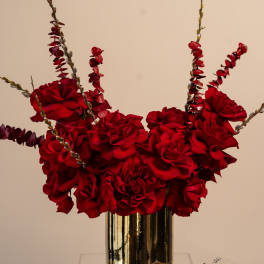 Red rose arrangement in a gold vase with tall branching stems
