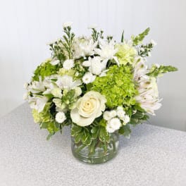 White and green floral arrangement in a clear glass vase