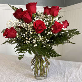 Red roses with baby's breath in a clear glass vase