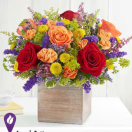 Mixed bouquet of red, orange, yellow, and purple flowers in a wooden box