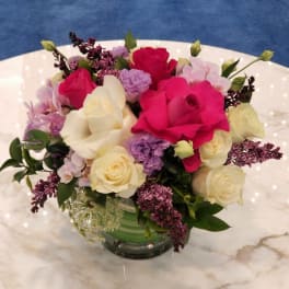 Mixed bouquet of pink, white, and lavender flowers in a glass vase