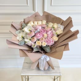 Bouquet of pink and cream flowers wrapped in tan paper