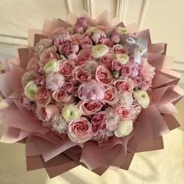Large pink bouquet of roses and ranunculus wrapped in pink paper
