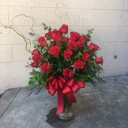 Red rose arrangement in a clear glass vase with a red ribbon