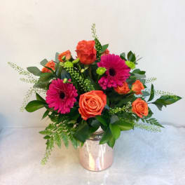 Bouquet of orange roses and pink gerbera daisies in a metallic vase