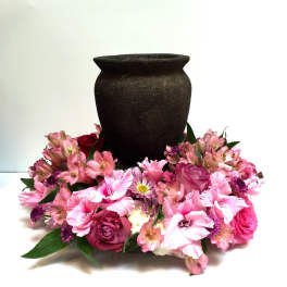 Pink floral arrangement around a dark urn-shaped vase