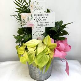 Potted plant arrangement with a memorial cross sign and pink ribbon