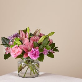 Pink lilies and roses in a clear glass vase