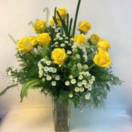 Yellow roses and white daisy flowers in a clear glass vase