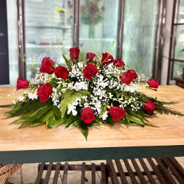 Low floral centerpiece with red roses, white filler flowers, and greenery