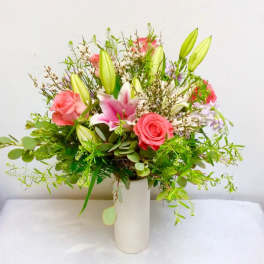 Pink roses and lilies arranged in a white vase