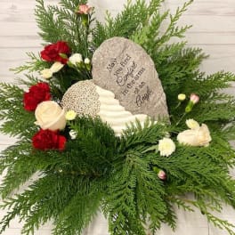 Sympathy floral arrangement with red and white flowers around a memorial stone