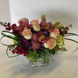 Bouquet of pink orchids and peach roses in a clear glass vase