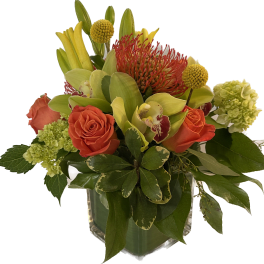 Orange roses and green orchids in a clear glass vase