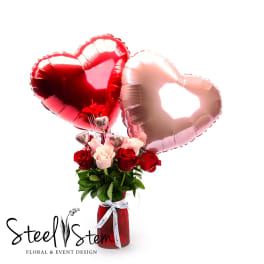 Red and pink roses in a vase with heart-shaped balloons
