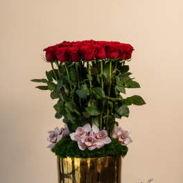 Tall arrangement of red roses with pale orchids in a gold vase
