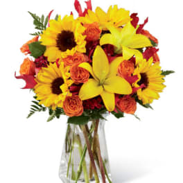 Sunflowers and orange roses in a clear glass vase