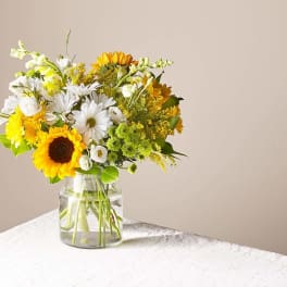 Bouquet of sunflowers and white daisies in a clear glass vase