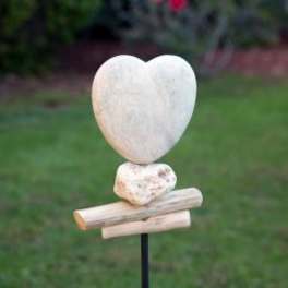 Heart-shaped stone sculpture on a metal stake outdoors