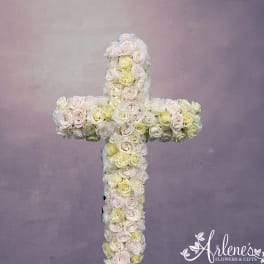 Cross-shaped floral arrangement of pale roses on a lavender background