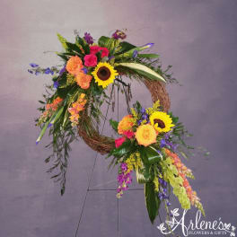 Colorful standing grapevine wreath with sunflowers, roses, snapdragons, and mixed blooms on a metal easel