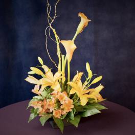 Orange calla lilies and peach flowers in a low black container