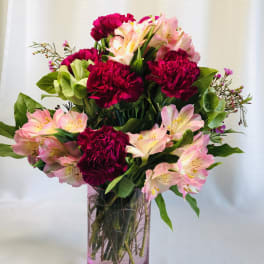 Pink and red bouquet of carnations and alstroemeria in a glass vase