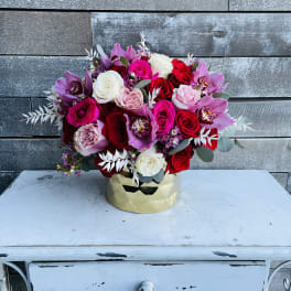 Bouquet of red, pink, white, and purple flowers in a gold container