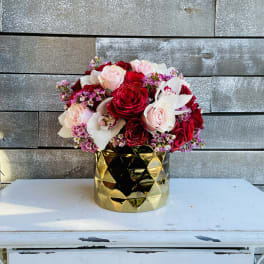 Bouquet of red and blush roses in a gold vase