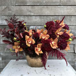 Deep burgundy and peach flowers arranged in a gold vase