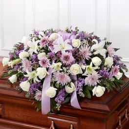 Large white and lavender floral spray on a casket