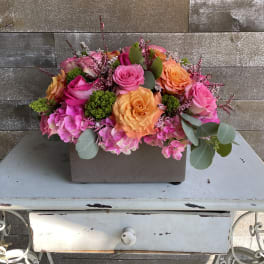 Pink and orange rose arrangement in a rectangular container