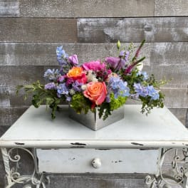 Colorful mixed flower arrangement in a square metal container