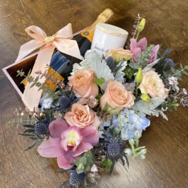 Bouquet with roses, orchids, and a champagne bottle in a gift box