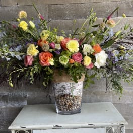 Large mixed floral arrangement in a clear vase with pebbles