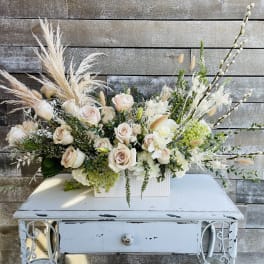 Cream rose arrangement in a white rectangular vase with airy pampas grass