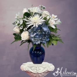 White and blue floral arrangement in a cobalt vase
